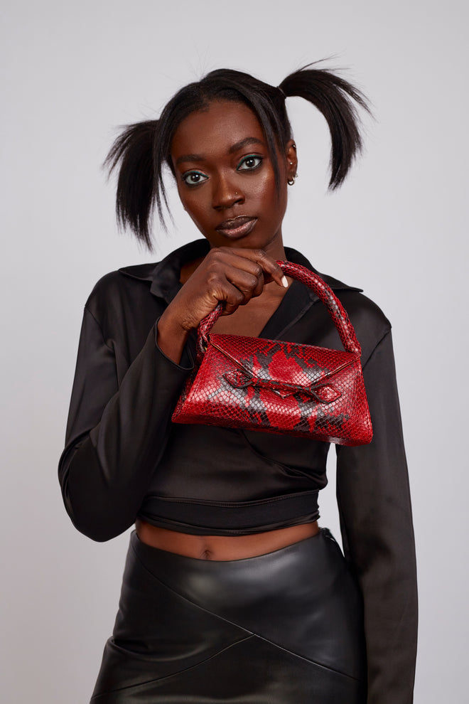 alt="A model showcasing a gorgeous red and black snakeskin mini bag with a sleek design and compact size, perfect for adding a bold touch to any outfit, available at Pink Maison"